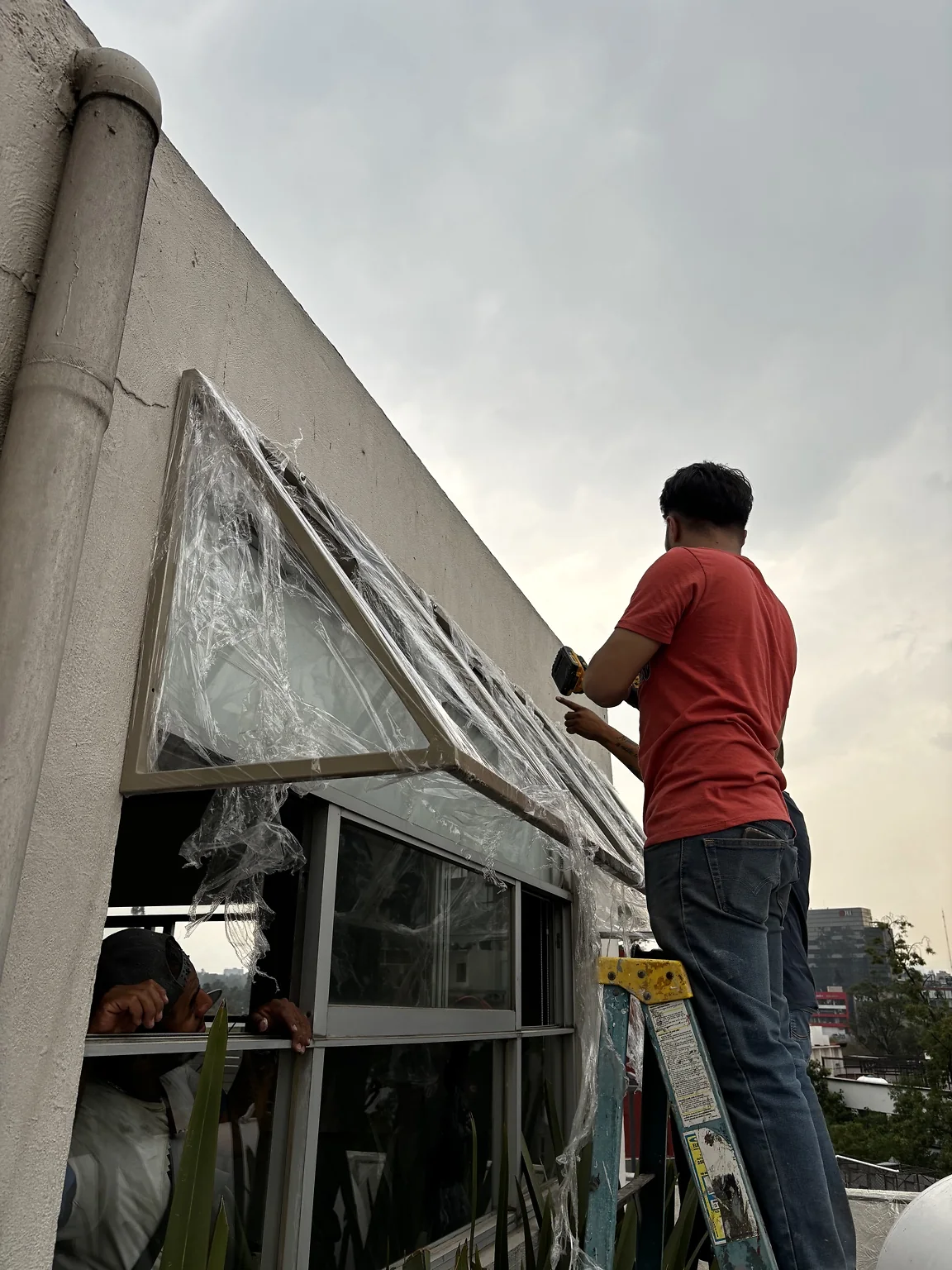 Instalación en sitio de una marquesina o cubierta triangular metálica sobre ventana exterior.