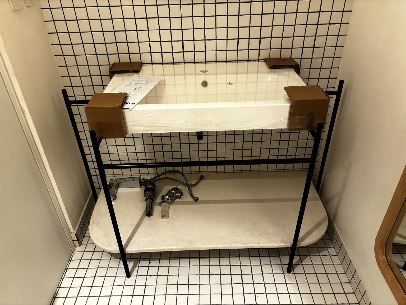 Mueble soporte para lavabo con estructura metálica negra instalado en baño.