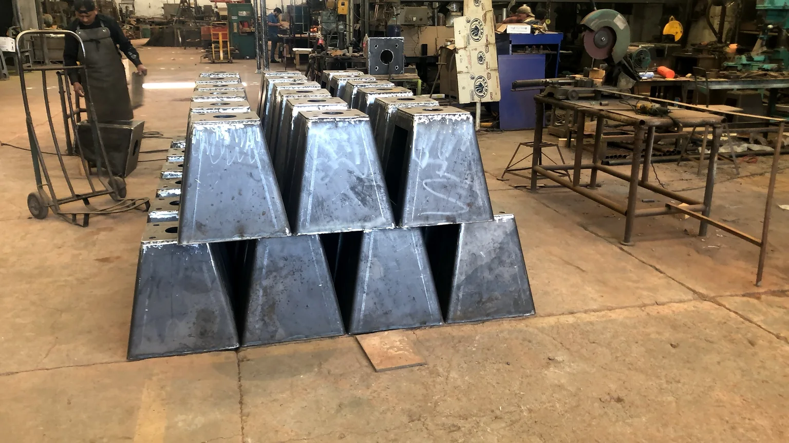 Lote de tolvas o cuerpos piramidales fabricados en acero y acomodados en serie dentro del taller.